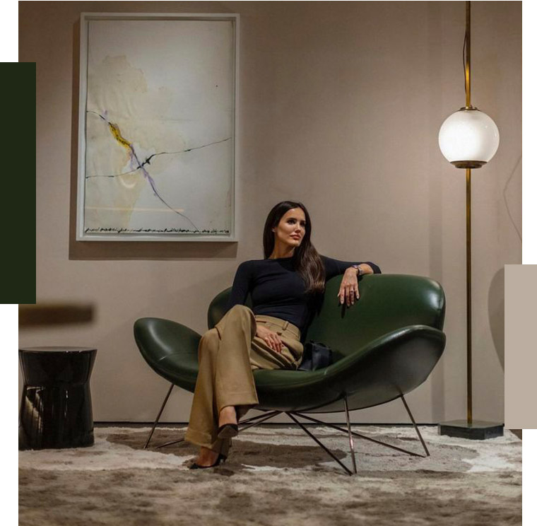 Woman seated in a green leather lounge chair beside a floor lamp